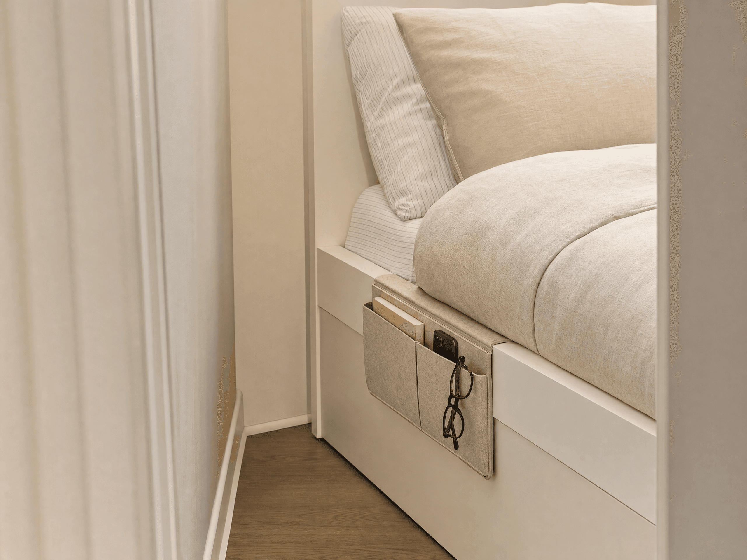 Bedside caddy holding essentials in a very small bedroom without a nightstand